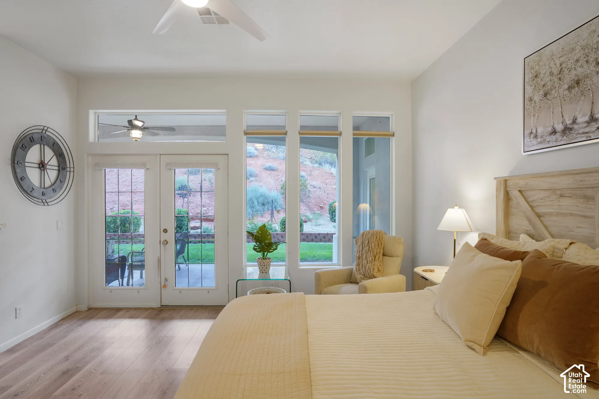 Wood-finish flooring, white walls, double glass-paneled doors, transom windows, and an overhead ceiling fan