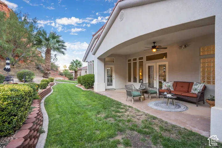 Covered patio with a ceiling fan, dual French doors, and glass block window accents