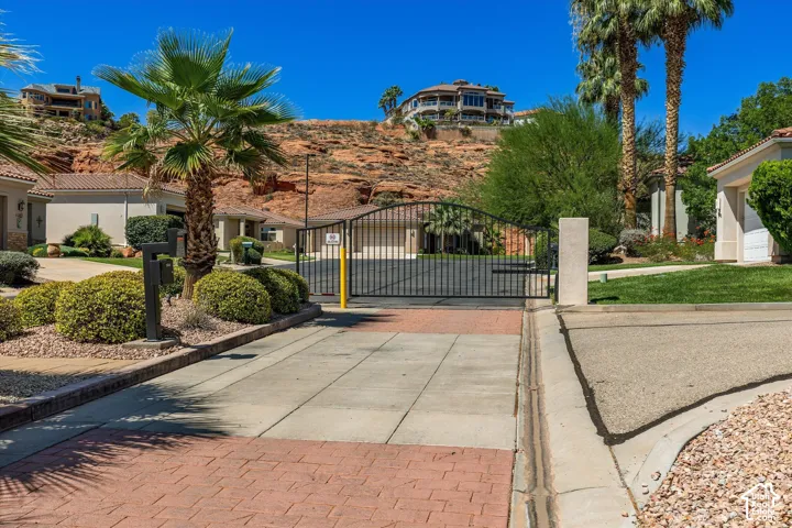 Gated community entrance featuring stamped concrete paving and mature landscaping