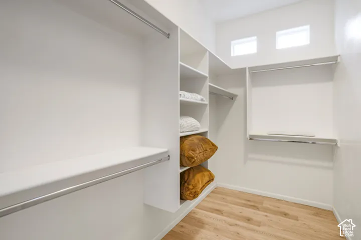 Custom closet organization system with wood-finish flooring, multiple shelving units, and integrated hanging rods