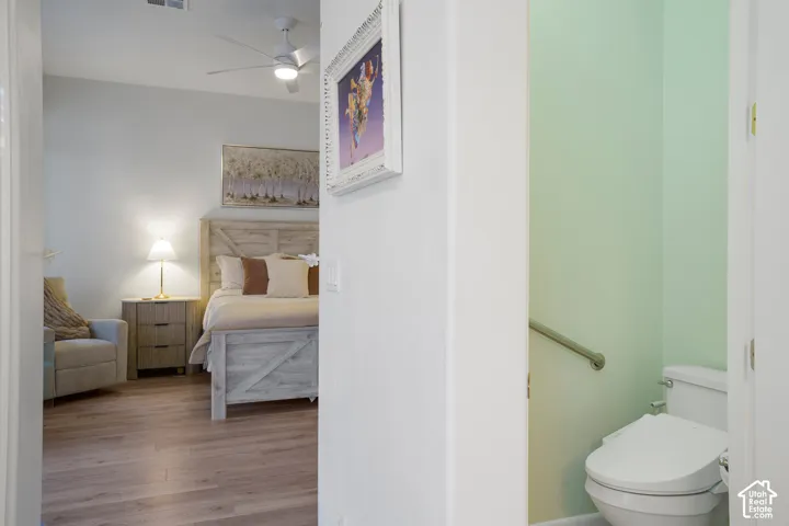 Wood-finish flooring throughout, ceiling fan with integrated lighting, and a private water closet with grab bar