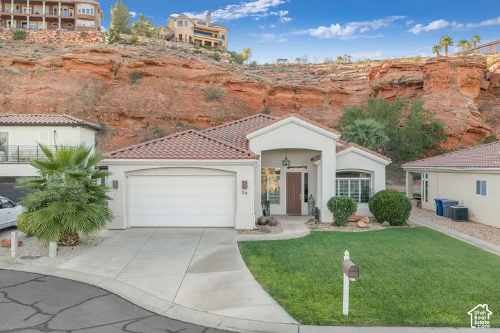 Stucco exterior residence featuring a tile roof, an integrated garage, and a concrete driveway
