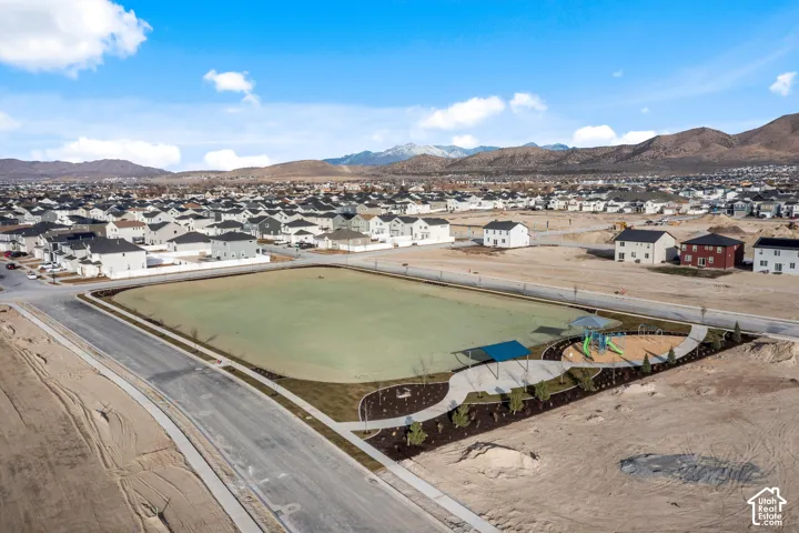 Expansive community green space featuring an integrated playground with shade structures and a paved walking path