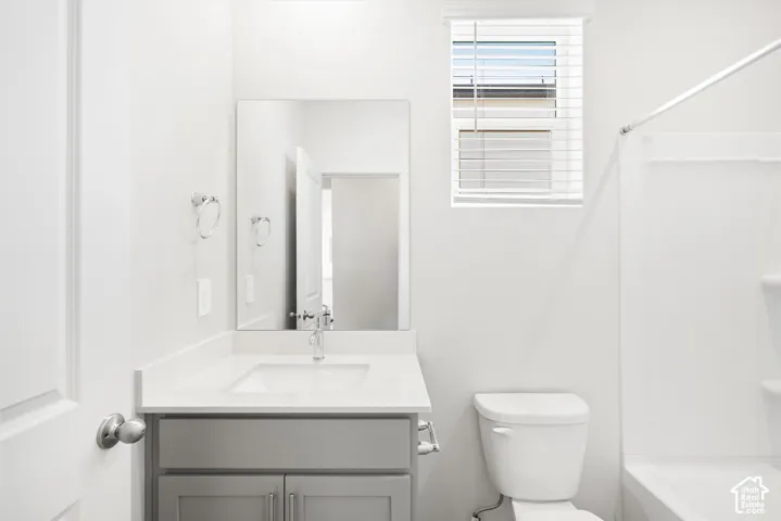 Vanity with light gray shaker cabinetry, white countertop, and undermount sink