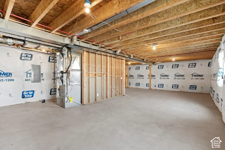 Unfinished basement offering exposed ceiling joists, concrete flooring, and partial wall framing