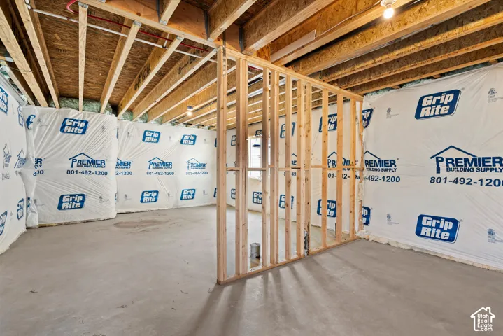 Unfinished basement with concrete flooring, exposed wood ceiling joists, and framed interior walls
