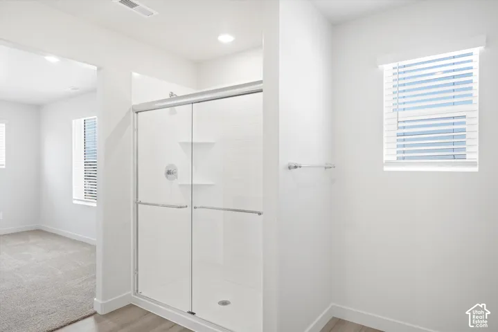 **DICSLAIMER** Interior package may vary.  Glass-enclosed shower with white subway tile, built-in shelving, and a chrome shower fixture