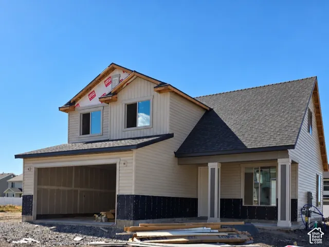 Two-story residence with light-colored siding, an attached garage, and a covered entry porch