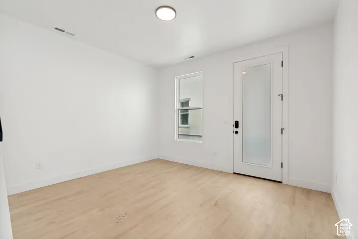 Recessed lighting, wood-finish flooring, white walls, and a frosted glass door