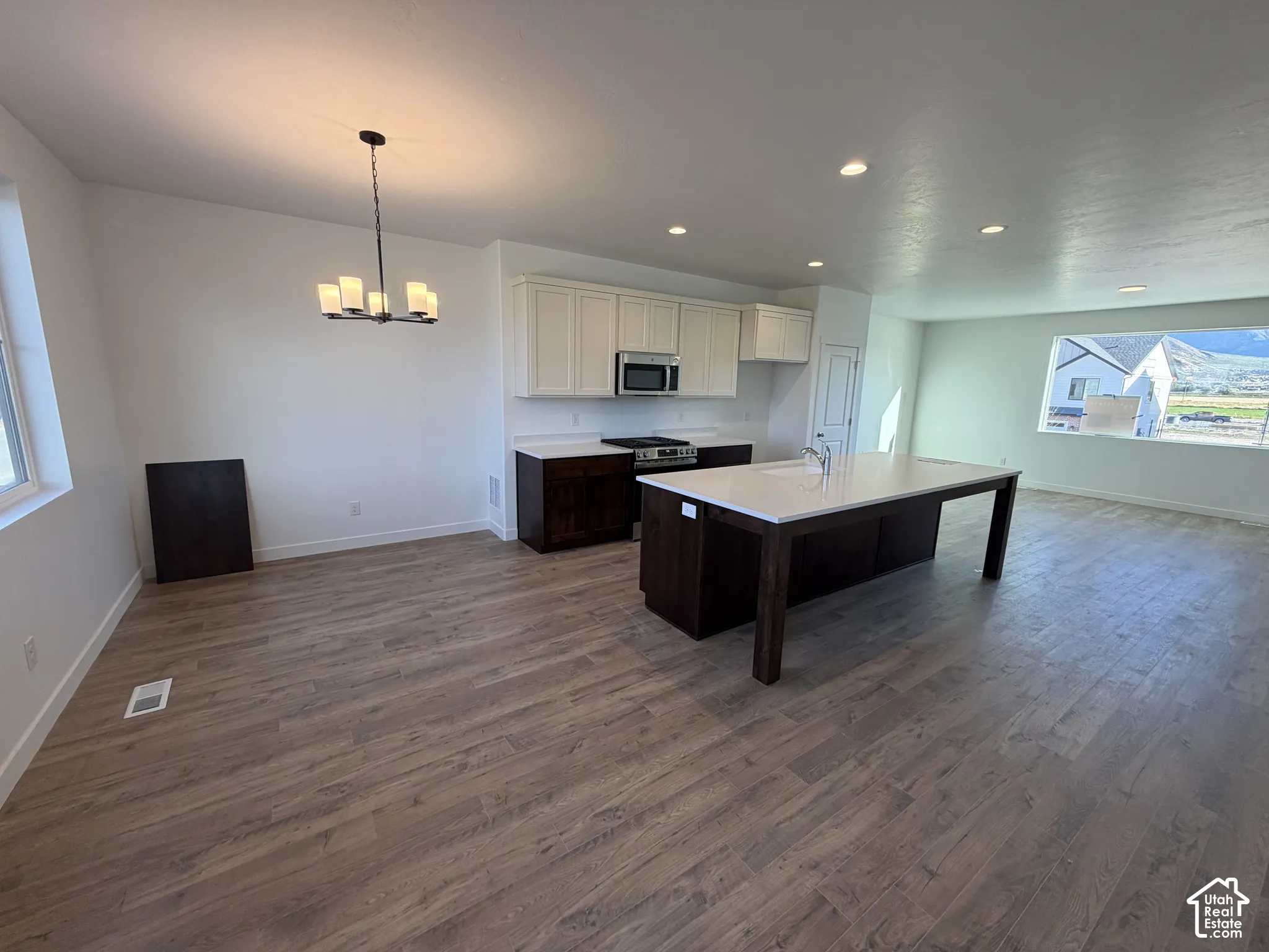 Open-concept layout featuring wood-finish flooring, recessed lighting, and a modern kitchen with a large island and white cabinetry