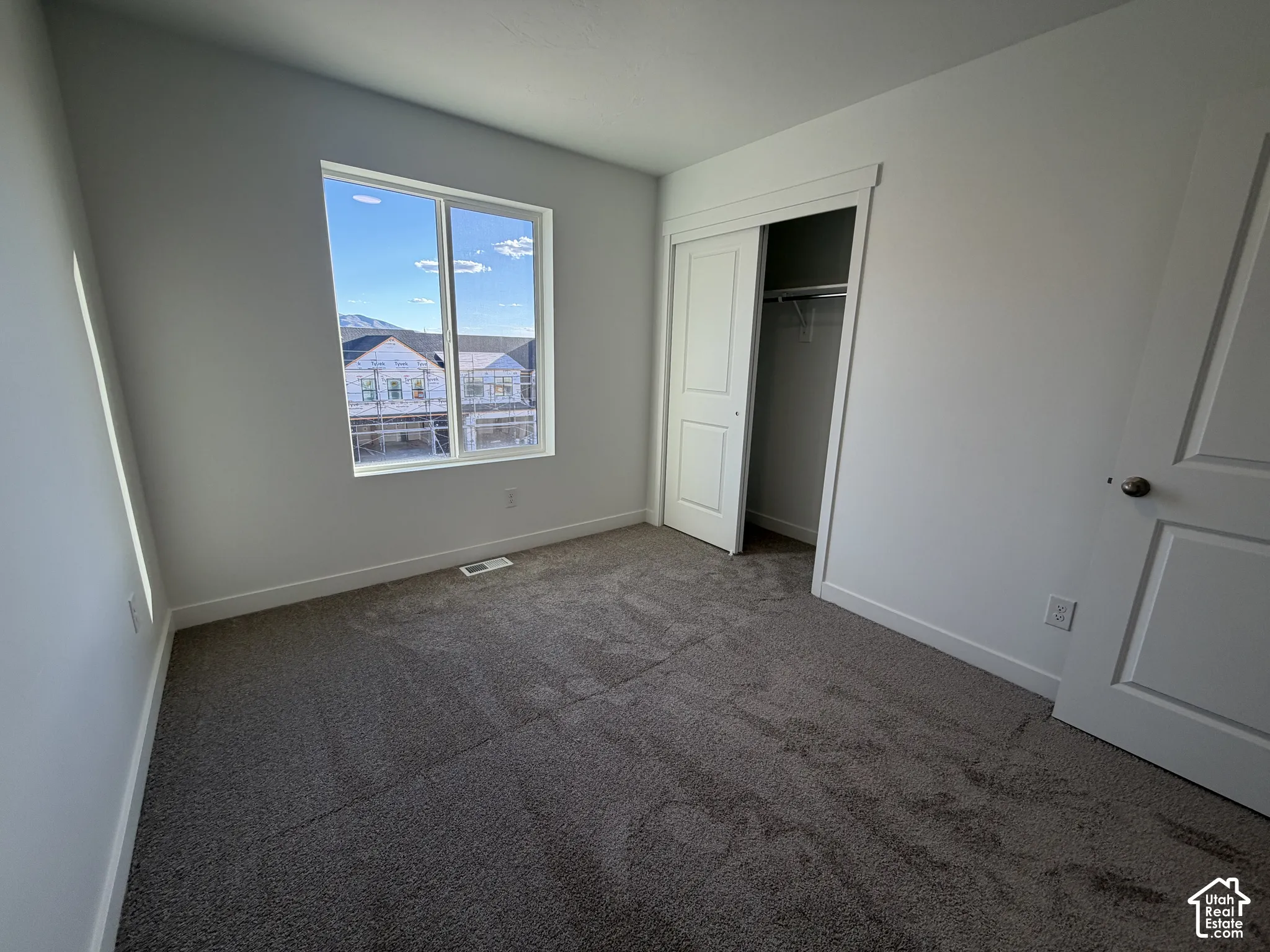 Neutral-toned carpeting, white walls, and a large window