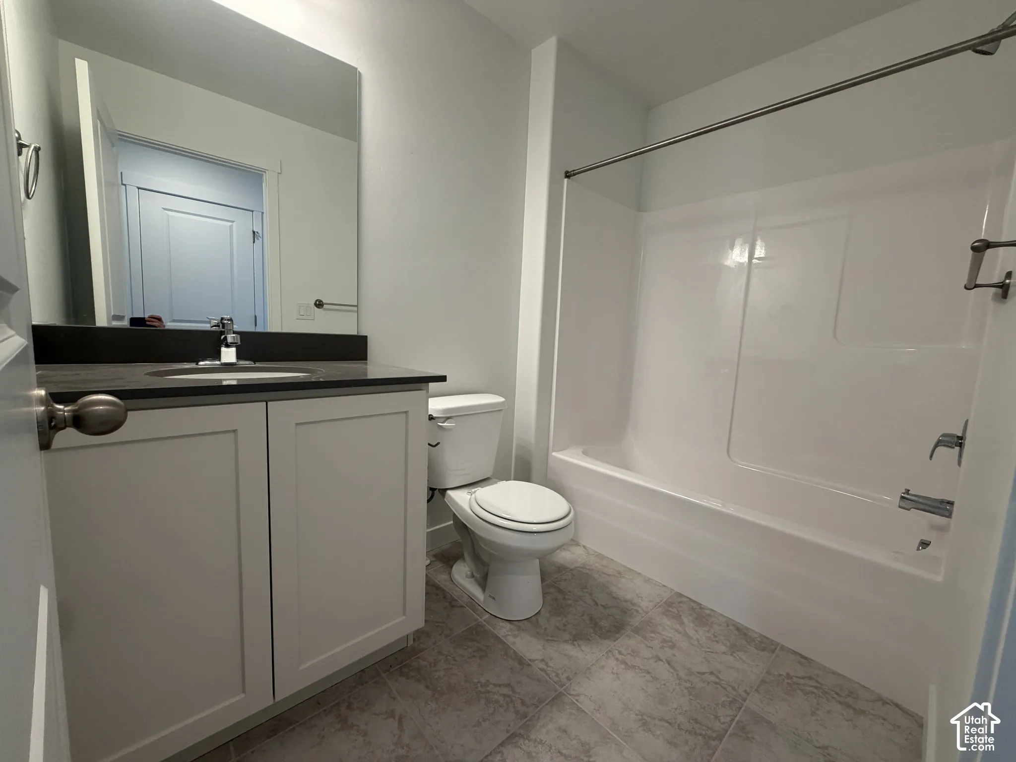 Vanity with light-colored cabinetry, dark countertop, and integrated sink