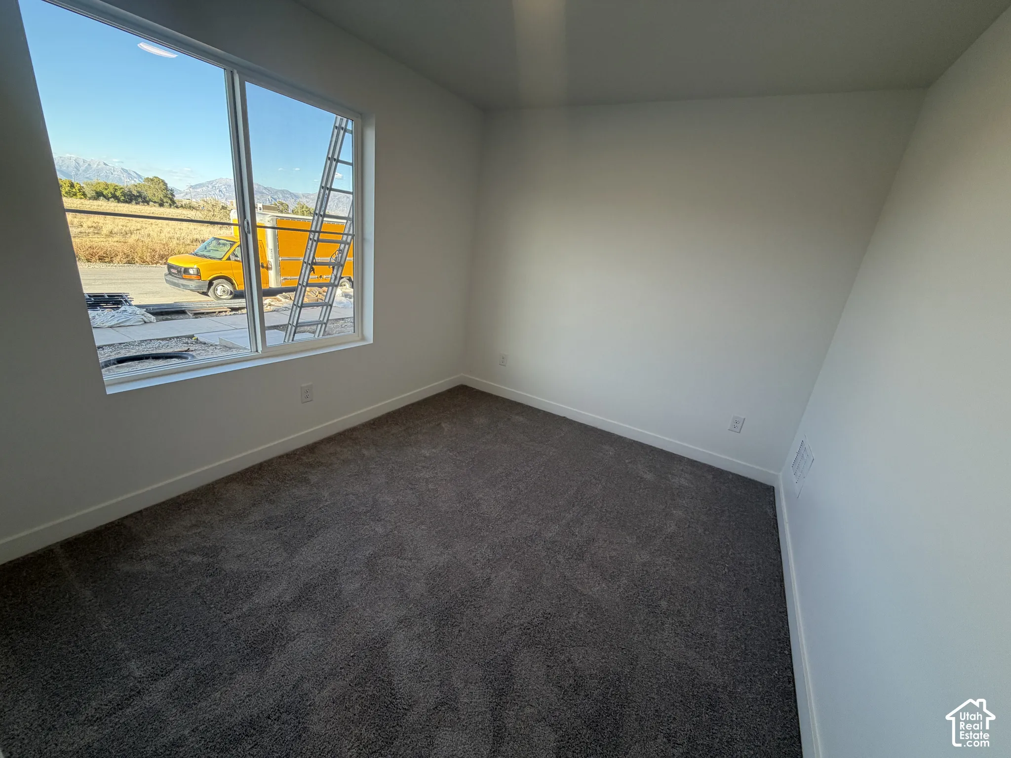 Spacious room with plush gray carpeting and white painted walls