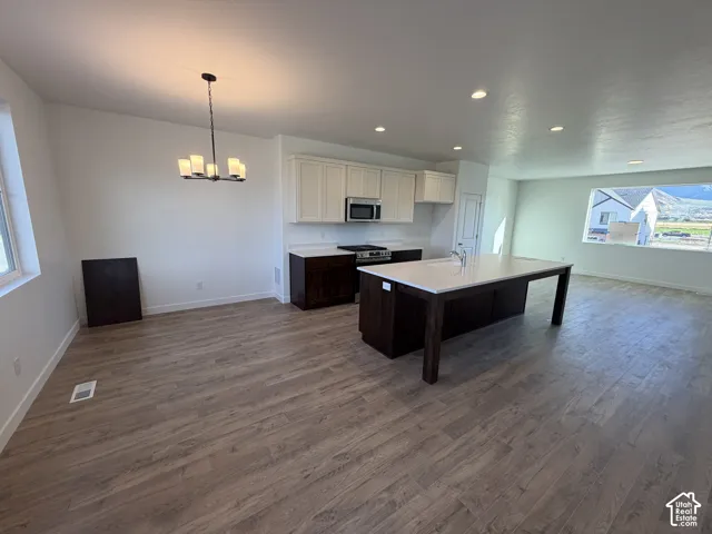 Open-concept layout featuring wood-finish flooring, recessed lighting, and a modern kitchen with a large island and white cabinetry