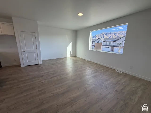 Spacious interior with wood-finish flooring, white walls, recessed ceiling lighting, and a large window
