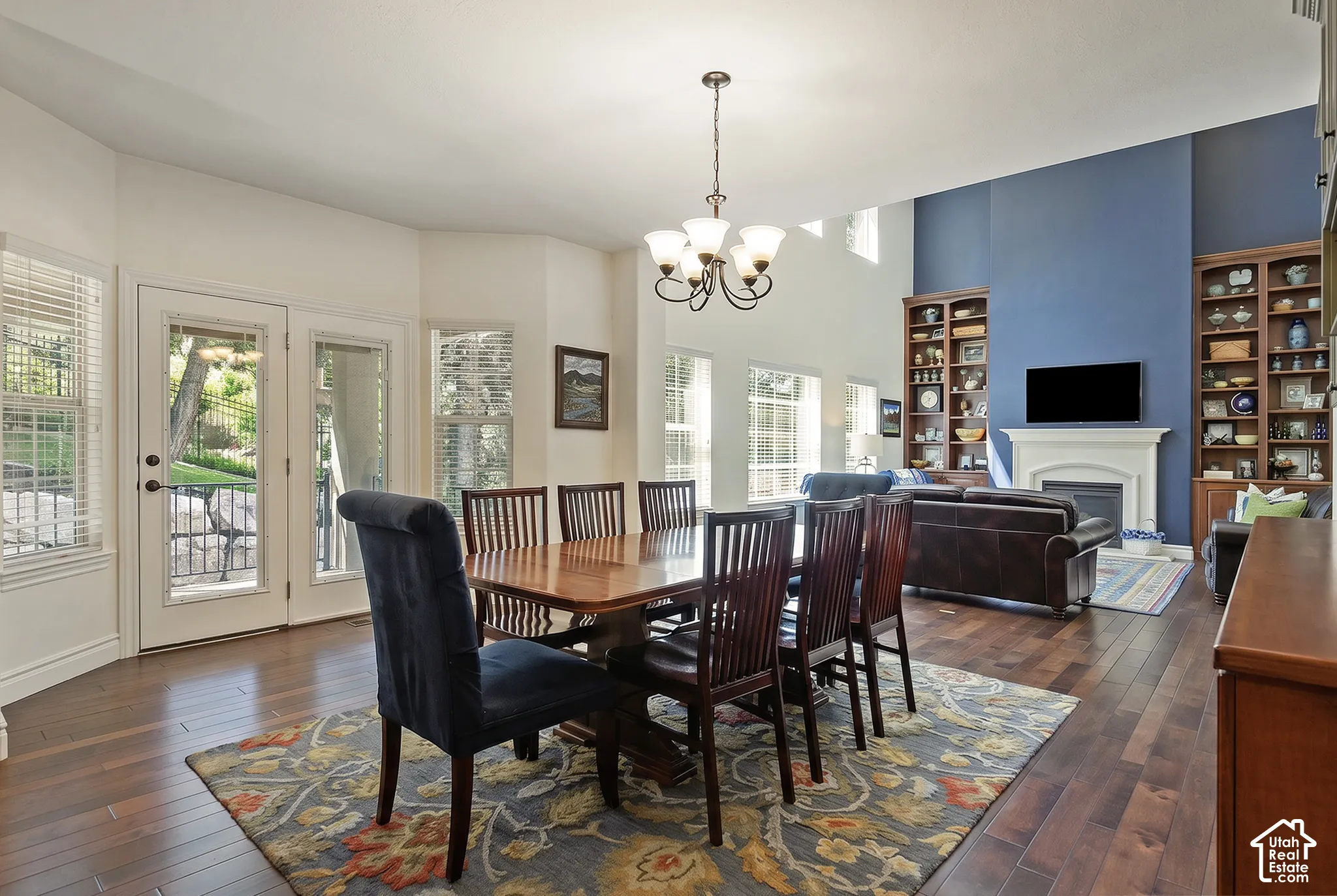Expansive room featuring wood-finish flooring, a neutral color palette, a fireplace with a white mantel, and built-in shelving