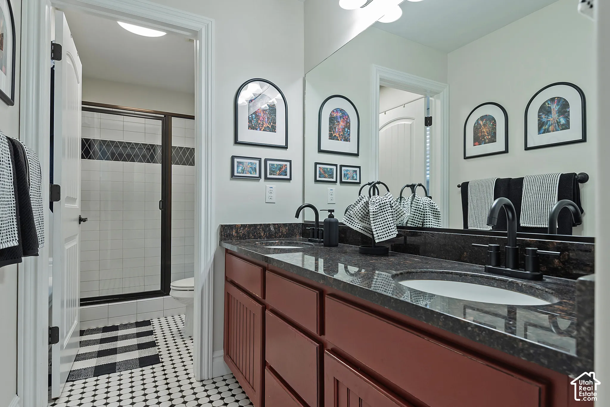 Dual vanity with dark granite countertops, under-mount sinks, and matte black fixtures
