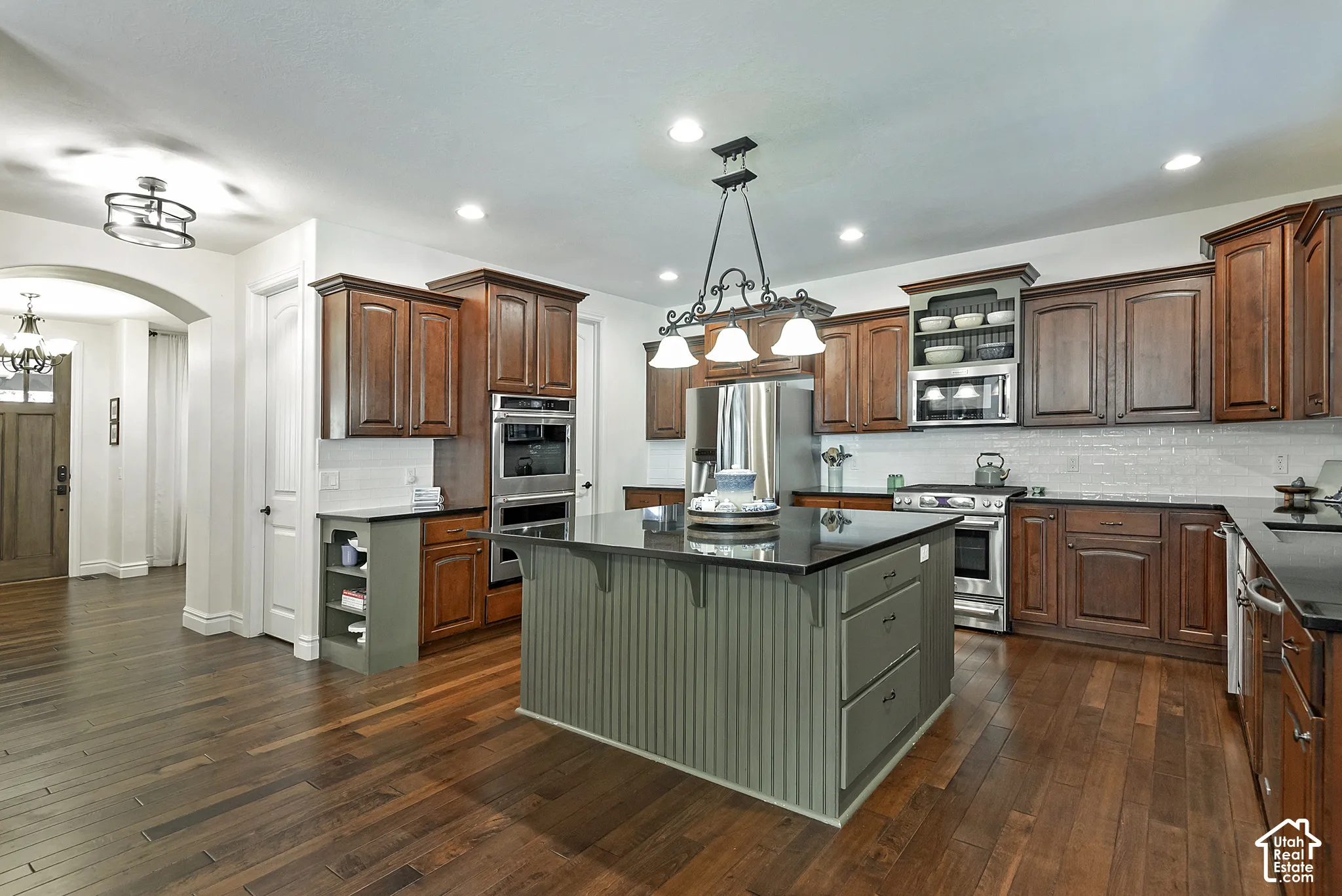 Kitchen featuring a central island with beadboard paneling, dark countertops, and wood-finish flooring