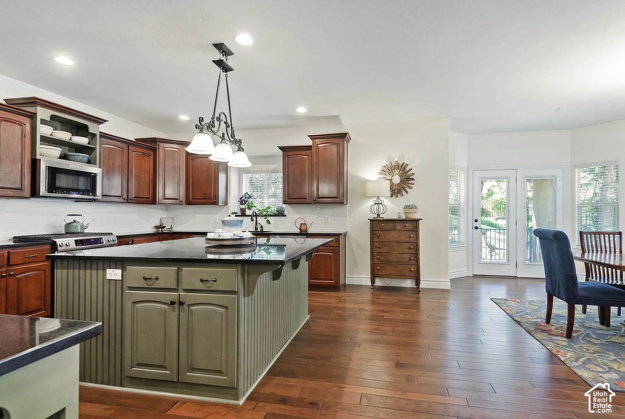 Kitchen featuring a central island with beadboard paneling, dark wood-finish cabinetry, black countertops, and a white subway tile backsplash