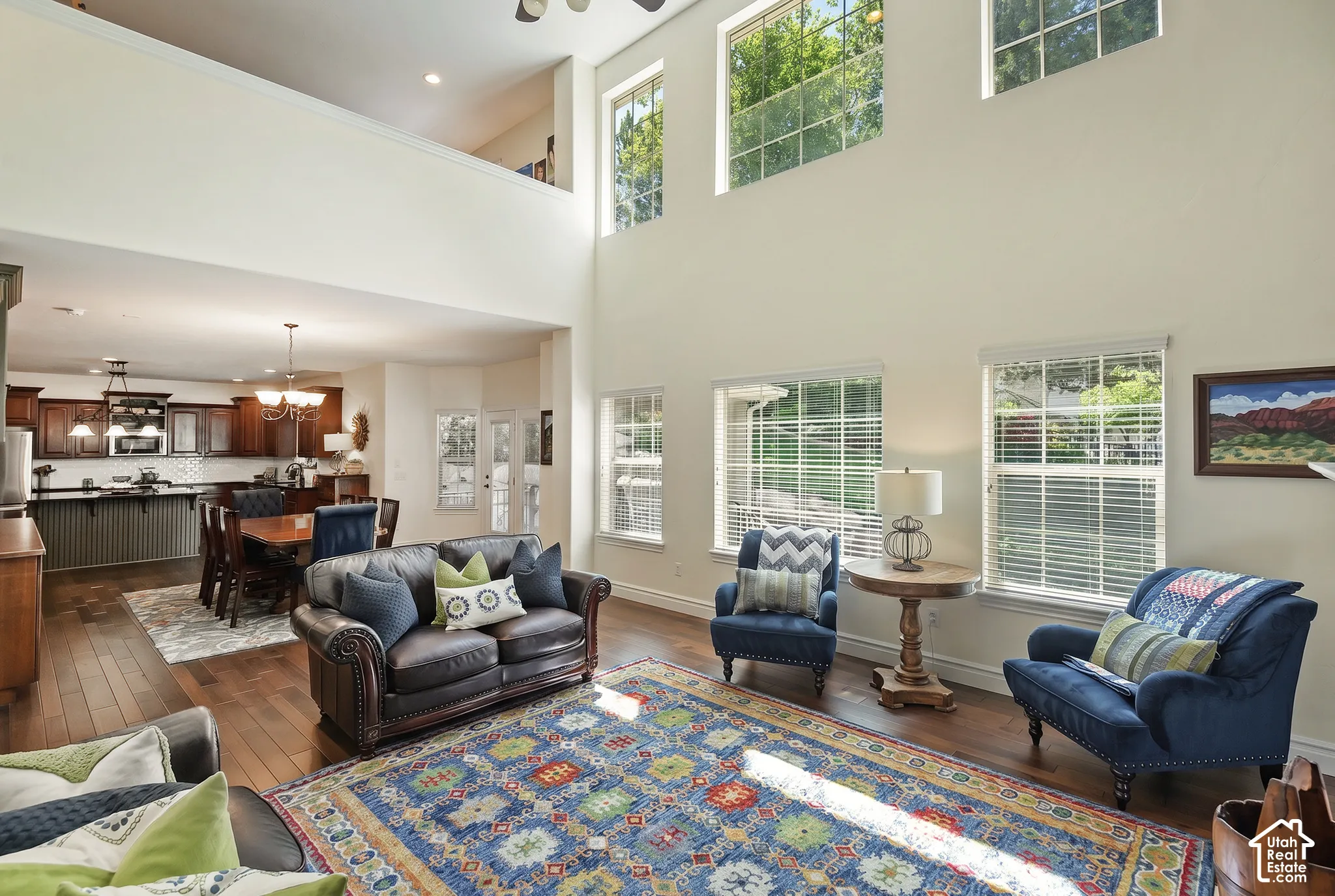 Two-story living area with high ceilings, multiple upper-level windows, and wood-finish flooring