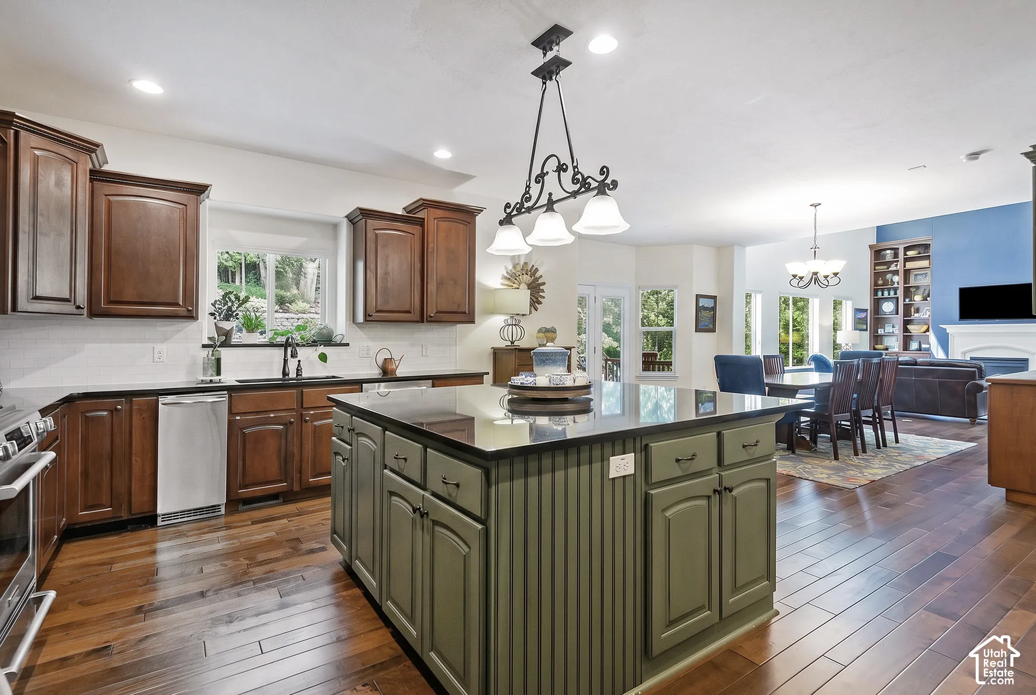 Hardwood-finish flooring throughout, kitchen island with beadboard paneling, stainless steel dishwasher, built-in shelving, and recessed lighting