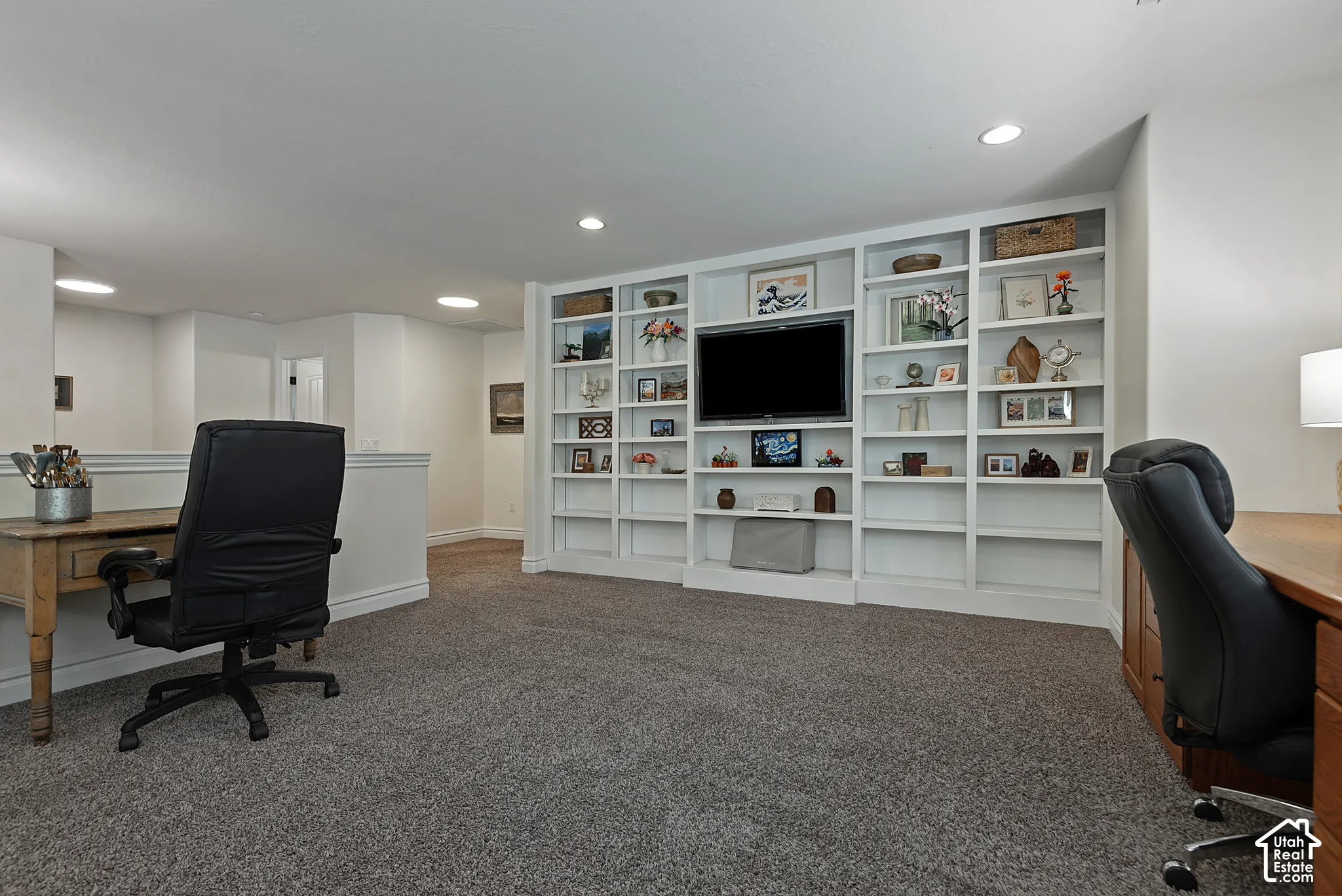 Built-in shelving with integrated media display, recessed lighting, and soft carpet flooring