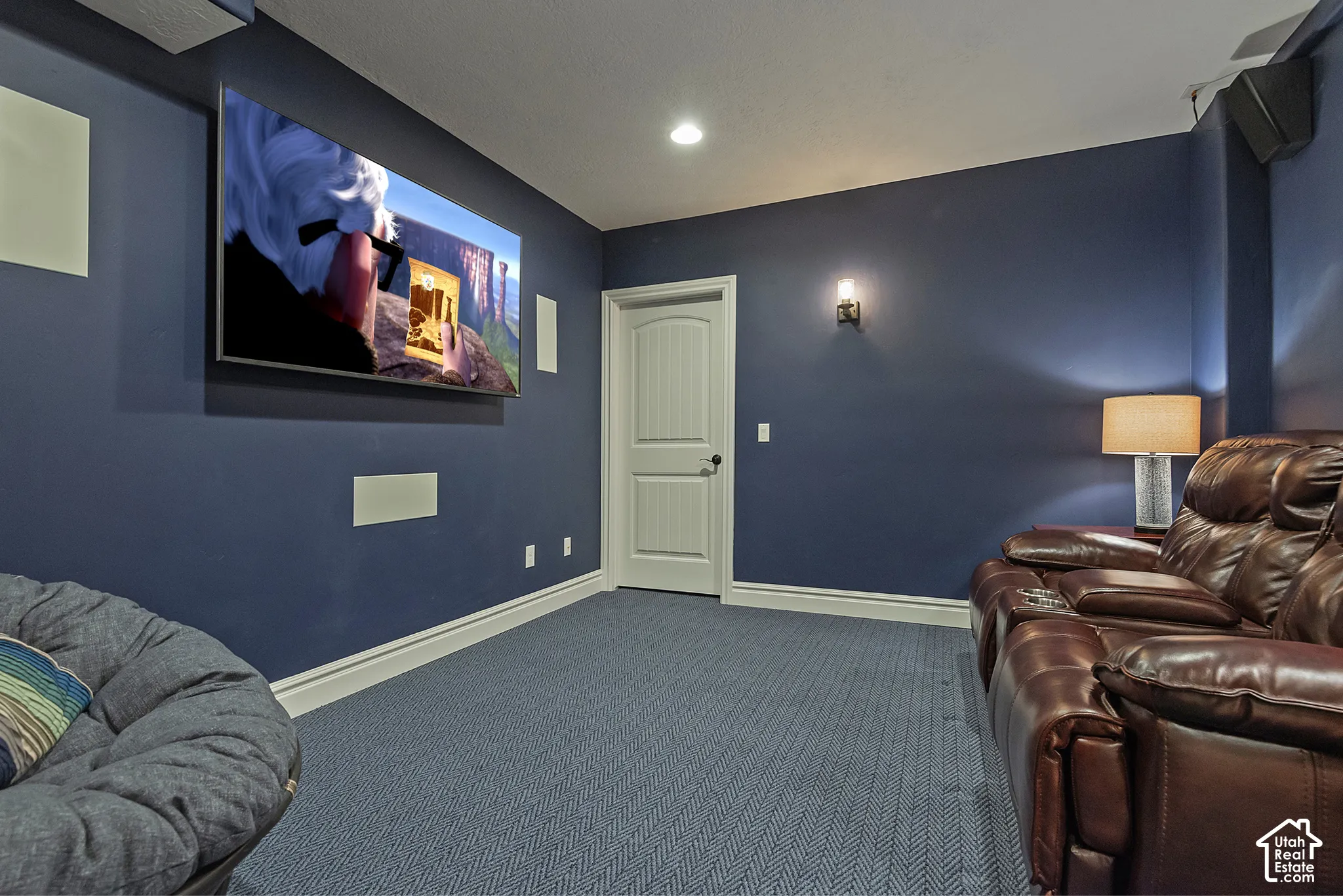 Blue wall paint, recessed lighting, wall-mounted television, built-in speakers, and blue patterned carpet