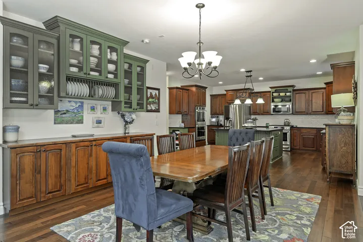 Hardwood-finish flooring, built-in cabinetry with glass-front uppers, recessed lighting, and a chandelier fixture