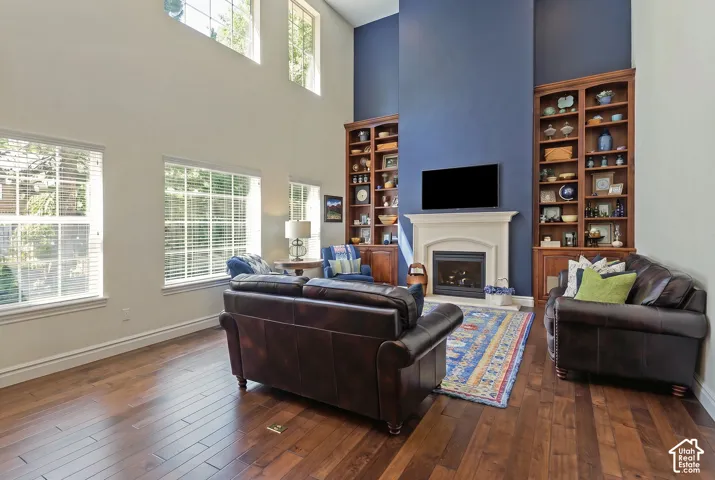 Hardwood-finish flooring, high ceilings, multiple windows, built-in shelving, and a fireplace with a stone surround