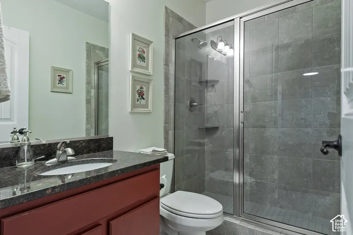 Spa-inspired bathroom featuring a walk-in shower enclosure with frameless glass doors and tile surround, dual vanity with dark cabinetry and stone countertop, and crisp white subway tile flooring