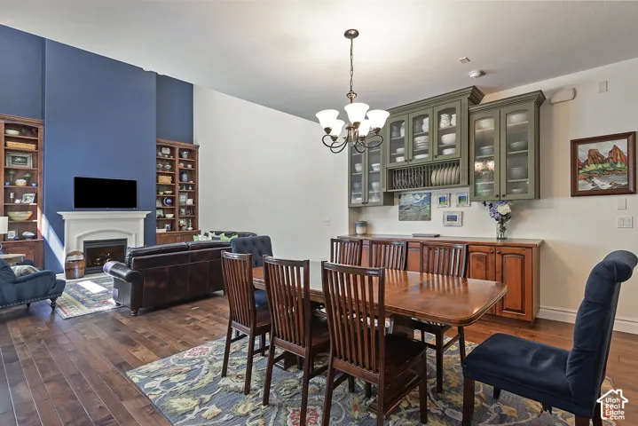 Hardwood flooring throughout, featuring a fireplace with a stone mantel, built-in shelving, an elegant chandelier, and custom display cabinetry