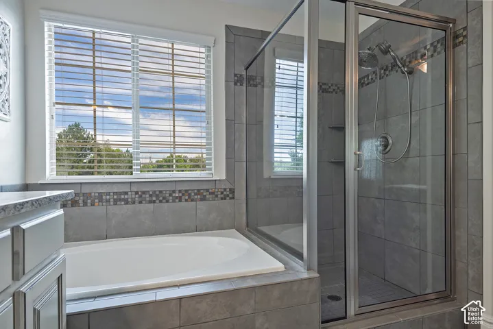 Tiled shower enclosure with a glass door, a separate soaking tub, and a window with blinds