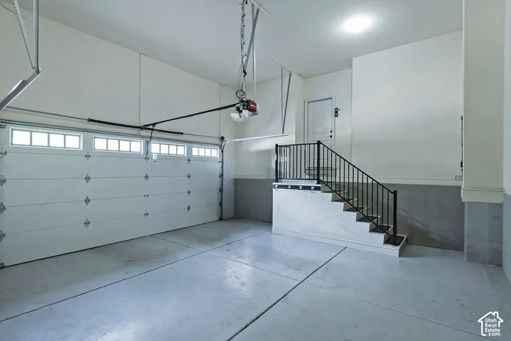 Attached garage with a white panel door, upper window inserts, and an automatic opener