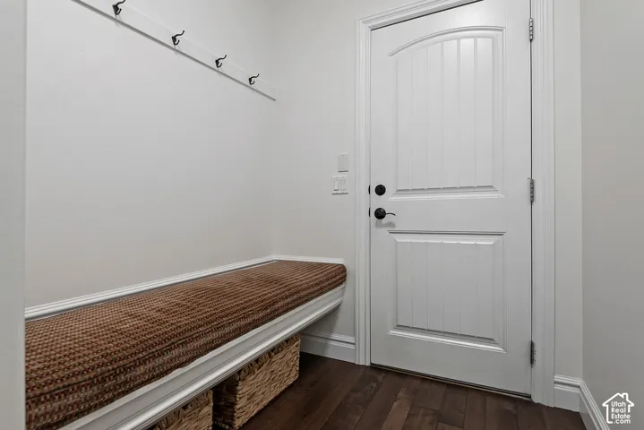 Built-in bench seating with a cushioned top, wall-mounted coat hooks, and wood-finish flooring