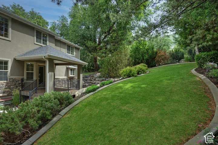 Expansive lawn with concrete curbing, mature trees, and layered landscaping
