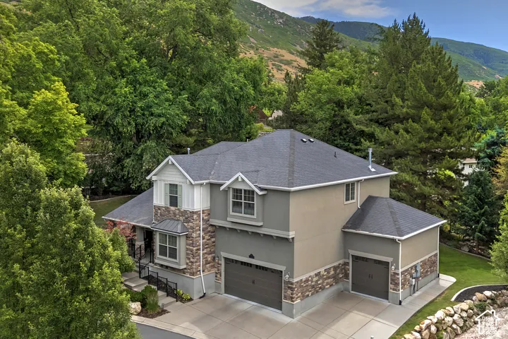 Two-story residence featuring a stone and stucco exterior, two-car garage, and an additional one-car garage