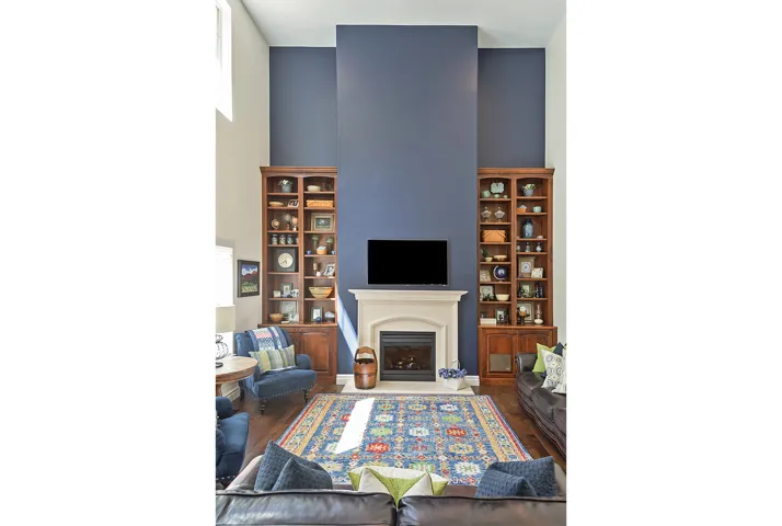 Two-story ceiling, a fireplace with a stone surround, and rich wood-finish flooring