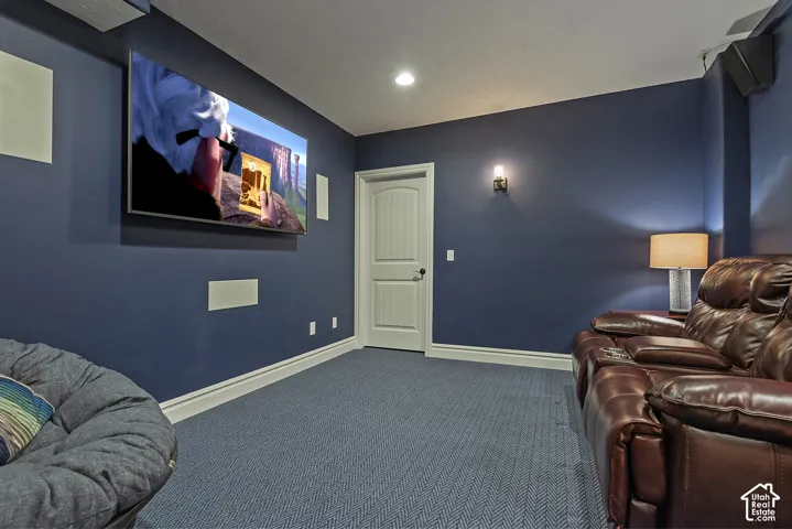 Blue wall paint, recessed lighting, wall-mounted television, built-in speakers, and blue patterned carpet