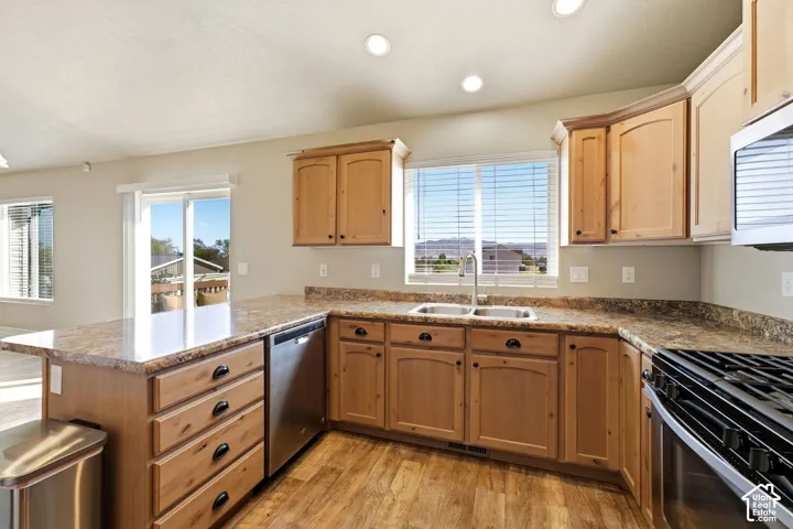 Kitchen with wood-finish flooring, light wood cabinetry, stone-finish countertops, stainless steel appliances, and recessed lighting