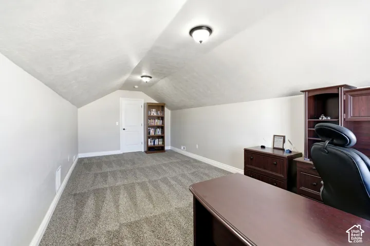 Attic space featuring sloped ceilings, textured ceiling finish, and gray carpet