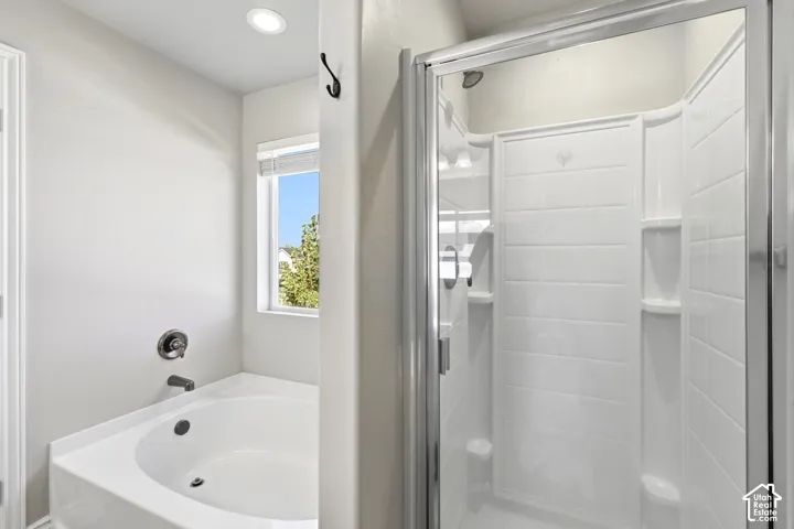 Built-in soaking tub with chrome fixtures, and a shower enclosure with glass doors and integrated shelving