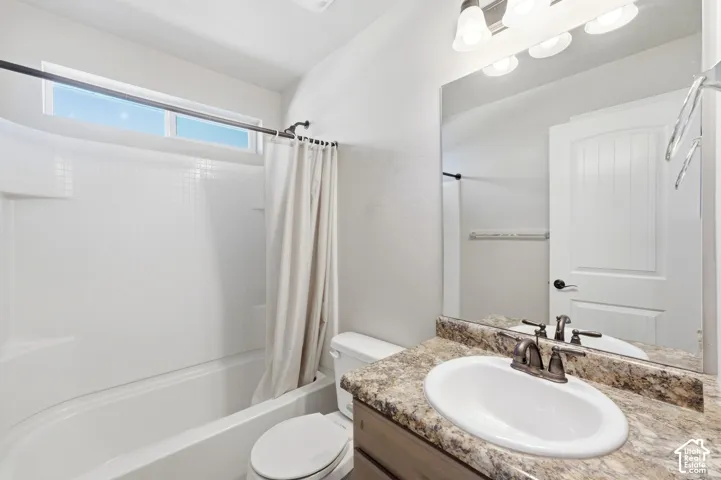 Bathroom featuring a vanity with a drop-in sink, a wall-mounted mirror, and a combination tub and shower