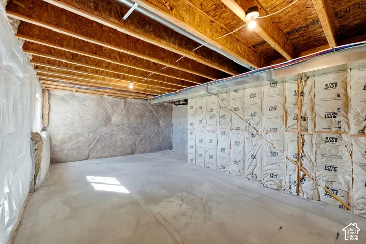 Unfinished basement with exposed wood joists, concrete flooring, and insulated walls