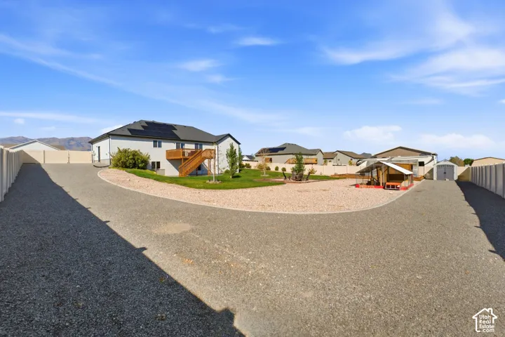 Gravel driveway leading to a two-story residence with a composite deck and external staircase