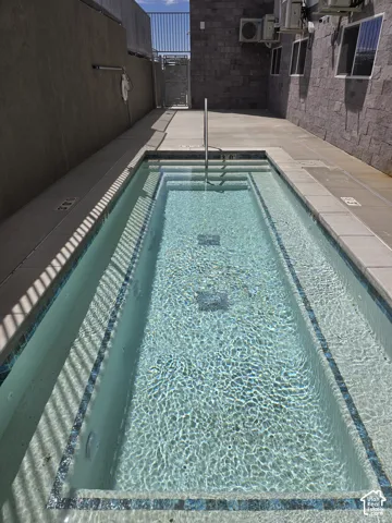 Plunge spa with tiled steps and integrated handrail, surrounded by concrete decking