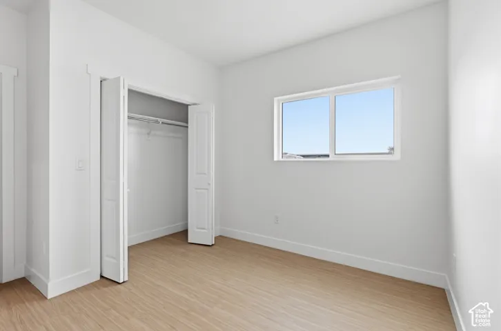 Light-filled room featuring wood-finish flooring, a double-pane window, and a bi-fold closet with an integrated hanging rod