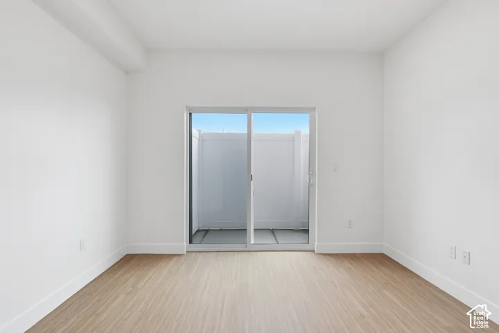 Expansive room featuring wood-finish flooring, white painted walls, and a sliding glass door
