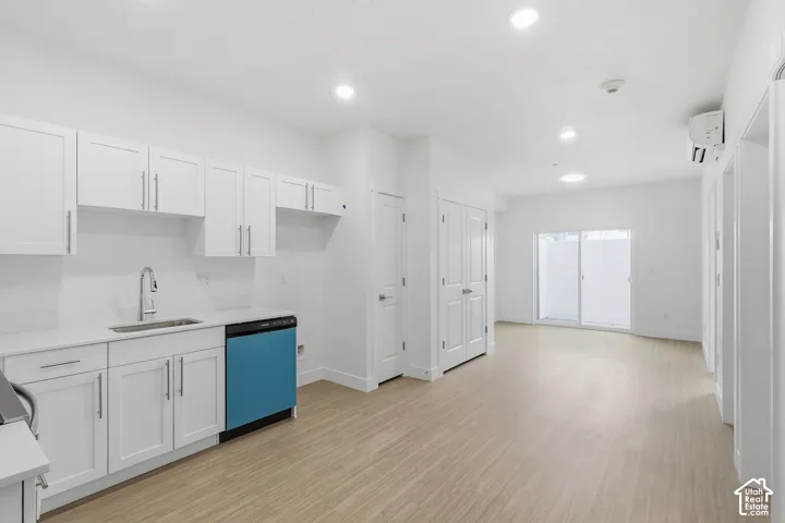 White shaker-style cabinetry with chrome hardware, light-toned wood-finish flooring, recessed lighting, and a sliding glass door