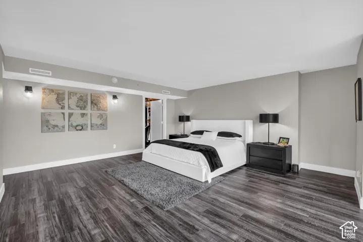 Wide-plank wood-finish flooring, light grey painted walls, built-in recessed lighting, and an open closet