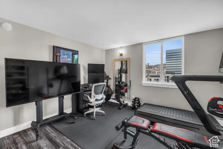 Room with wood-finish flooring, light gray wall paint, and a window with a cityscape backdrop